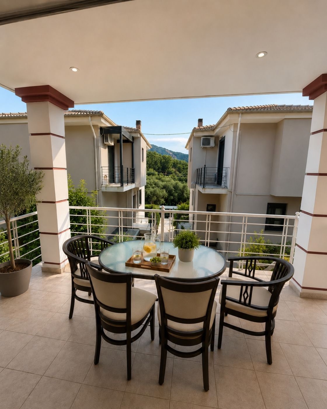 Shaded veranda at Natura Garden Villas with a dining table and mountain views over Parga